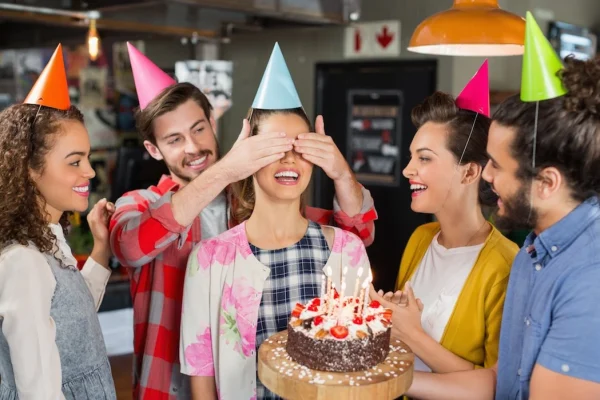 happy-friends-with-cake-giving-suprise-to-woman-during-her